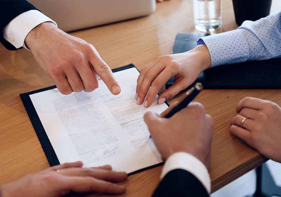 man signing papers with attorneys